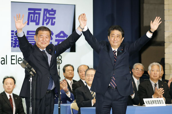 党総裁選を終え石破元幹事長（左）と手を取り合う（Ｃ）共同通信社