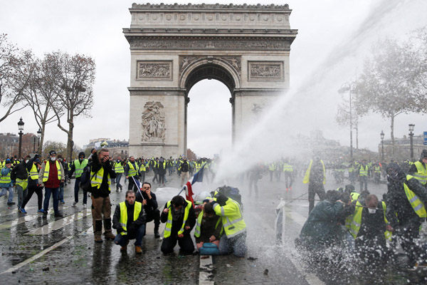 パリの凱旋門前で警察当局の放水を受けるデモ参加者（Ｃ）ロイター＝共同