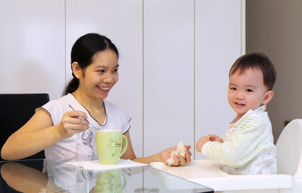 赤ちゃんに朝食を食べさせるフィリピン人家政婦（シンガポール）／（Ｃ）共同通信社