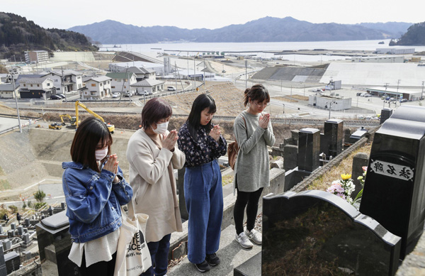 震災から８年になる前日、岩手県大槌町の高台にあるお墓を訪れ手を合わせる親子（Ｃ）共同通信社