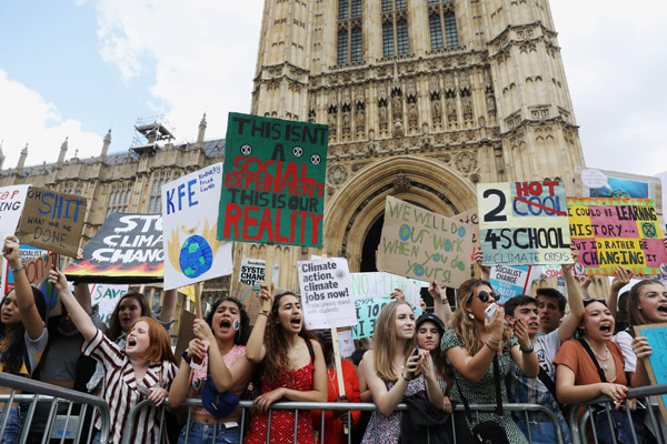 ロンドンの国会議事堂前で行われた温暖化対策を求めるデモで、プラカードを掲げる参加者ら（Ｃ）ロイター・共同
