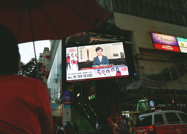 街頭のスクリーンに映し出されたニュースを見る人々（Ｃ）ロイター