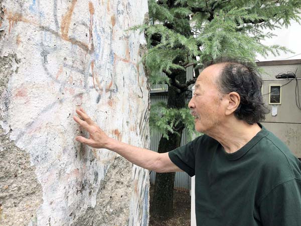 “ベルリンの壁”を指でなぞるイラストレーターの黒田征太郎氏（提供写真）