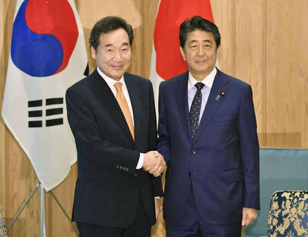 会談前に握手する韓国の李洛淵首相（左）と安倍首相（Ｃ）共同通信社