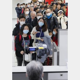 中国・武漢から成田空港に到着し、検疫を通過する乗客ら。手前は体温を測定するサーモグラフィー＝２３日（Ｃ）共同通信社