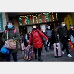 マスクを装着し荷物を持って歩く人たち（30日、北京駅）／（Ｃ）ロイター