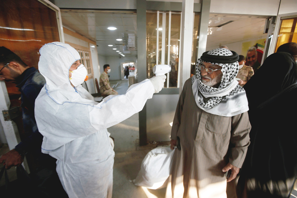 イランとイラクの国境ゲートで乗客の体温をチェックするイラクの医療スタッフ（Ｃ）ロイター／Essam al-Sudani