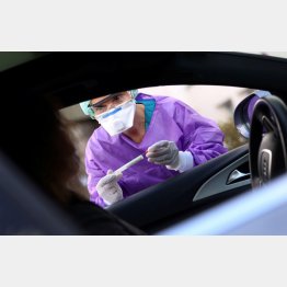 車に乗ったまま新型コロナウイルス感染の検査を受ける市民（手前）と医療従事者＝独フランクフルト近郊の病院で（Ｃ）ロイター＝共同
