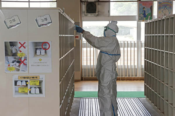 生徒の新型コロナウイルス感染が確認された、市立中学校の校内を消毒する作業員（Ｃ）共同通信社