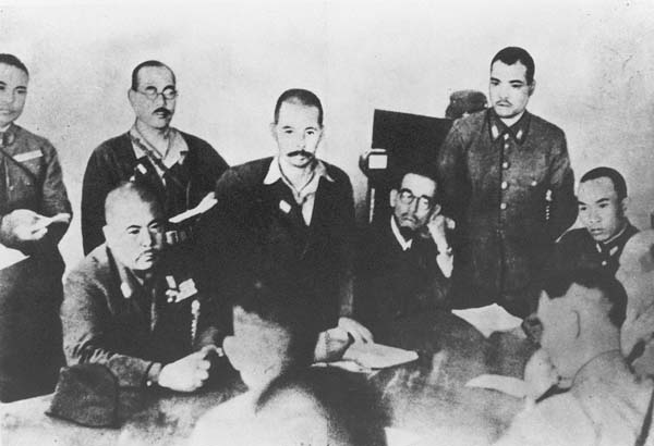 1942年2月15日、パーシバルと会見。写真は山下奉文軍司令官（向こう側左端の着席している人物）に降伏を申し入れるパーシバル英軍司令官（手前右）。山下の隣に立っているのは通訳を務めた情報参謀の杉田一次中佐（シンガポール・ブキテマのフォード事務所）／（Ｃ）共同通信社