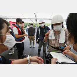 熊本県人吉市で、ヘルメットをかぶりボランティアの受け付けをする人たち（Ｃ）共同通信社