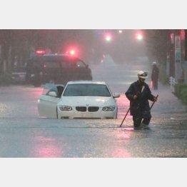 大雨の影響でマンホールから噴き出した水で道路が冠水し水没する車両（Ｃ）日刊ゲンダイ