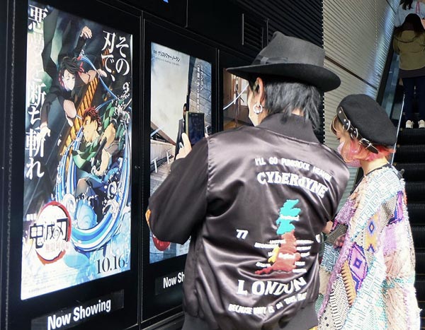 公開初日を迎えたアニメ映画「劇場版『鬼滅の刃』無限列車編」のポスターの写真を撮る人たち（東京・新宿）／（Ｃ）共同通信社
