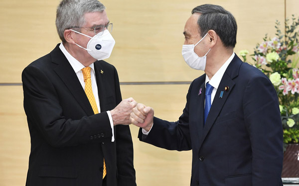 16日、会談を前にIOCのバッハ会長（左）とグータッチをする菅首相（Ｃ）共同通信社