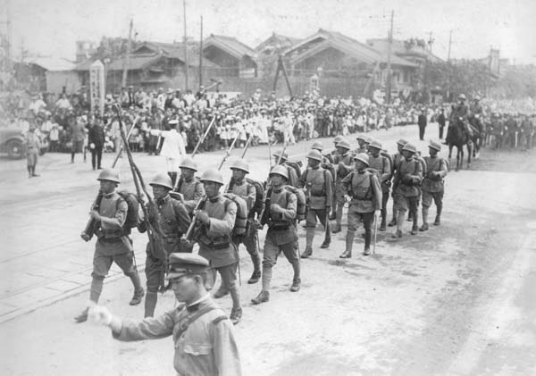 満州事変1周年記念日に、名誉の軍旗を掲げて大阪市内を行進する歩兵第8連隊（1932年9月18日＝日本電報通信社撮影）