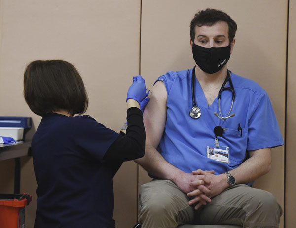 米コロラド州で、新型コロナウイルス感染症ワクチンの接種を受ける医師（右、ERILEE・BENNETT／THE GAXETTE・ＡＰ＝共同）