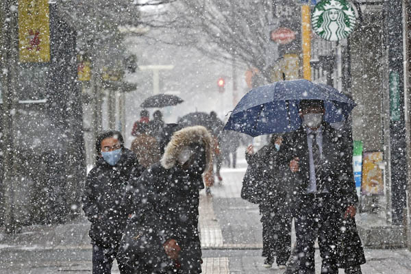 8日、雪が降る中、福岡市の繁華街・天神を歩く人たち（Ｃ）共同通信社