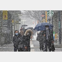 8日、雪が降る中、福岡市の繁華街・天神を歩く人たち（Ｃ）共同通信社