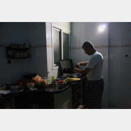 停電中にバッテリーでLEDライトをつけ料理するサミール（2014年）／（撮影）藤原亮司