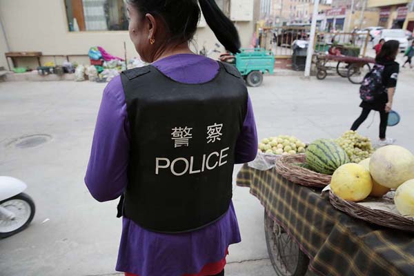 当局から配布された「POLICE」と書かれた防弾衣を着て商売をするウイグルの女性（2018年）／（撮影）川嶋久人