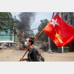 クーデターで混乱するミャンマーのヤンゴンで国民民主連盟（NLD）の旗を掲げる男性（Ｃ）ロイター