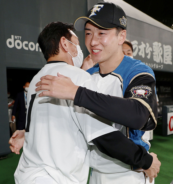 試合後、場内を一周した斎藤（右）と抱き合う栗山監督（球団提供）