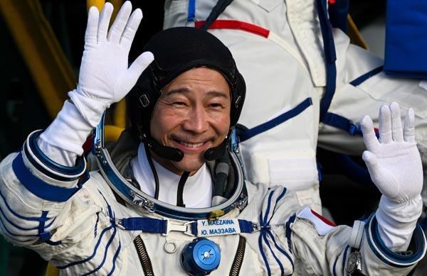 ８日、カザフスタンのバイコヌール宇宙基地で、宇宙船に乗り込む前に手を振る前澤友作氏（代表撮影・タス＝共同）