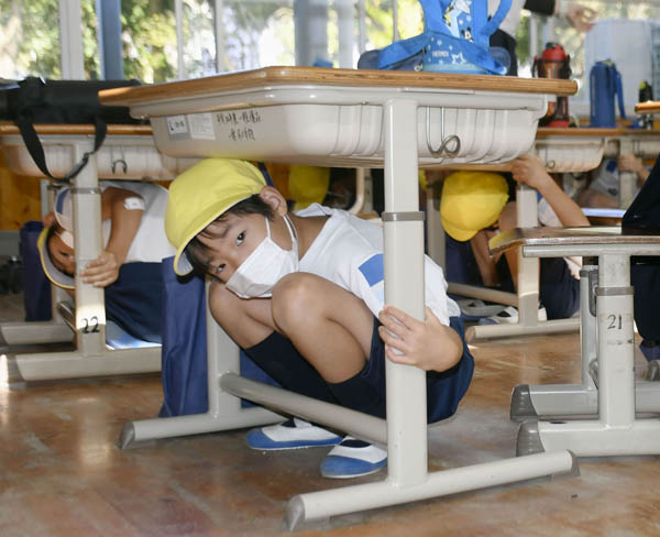 南海トラフ巨大地震を想定した防災訓練が行われた小学校で、机の下に身を隠す児童（Ｃ）共同通信社