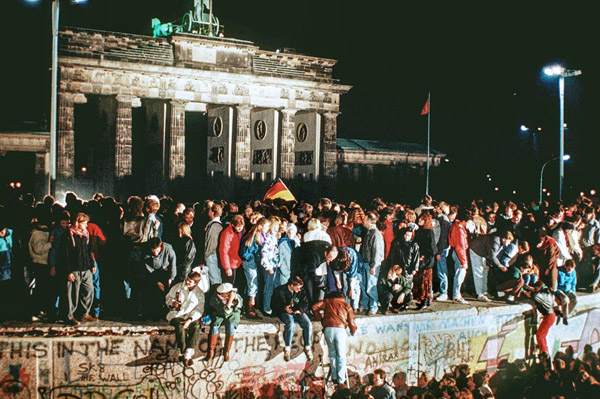 1989年11月、ベルリンの壁が崩壊。壁の天辺に立ち上がり、自由を噛みしめるたくさんの人々（DPA提供・AP＝共同）