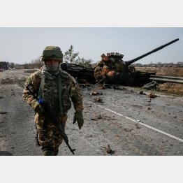 キエフ地域の戦場の最前線、破壊したロシア軍の戦車の前を歩くウクライナ兵（Ｃ）ロイター