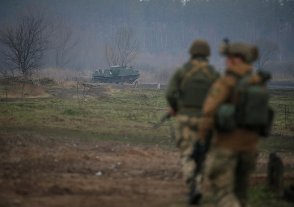 ロシアの攻撃が続くなか、キエフ近郊の最前線で破壊され放置されたロシア軍装甲兵員輸送車（APC）の側を警戒しながら監視するウクライナ軍メンバー（Ｃ）ロイター