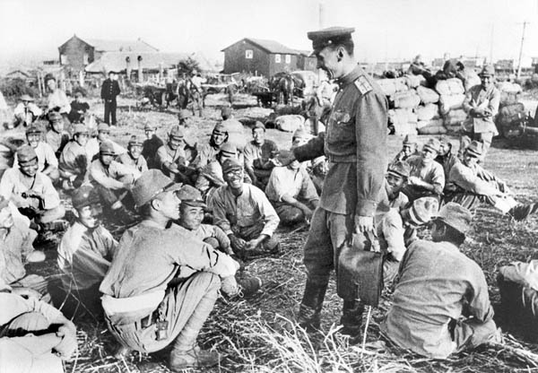 満州で武装解除され、ソ連軍将校の説明を聞く関東軍兵士たち。厳しい抑留生活が始まるとは知らず、表情には明るさも（1945年、ノーボスチ＝共同）
