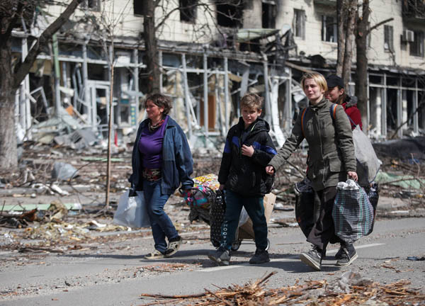 ウクライナ東部マリウポリ、破壊された街の通りに沿って自分たちの荷物を運ぶ住民たち（Ｃ）ロイター