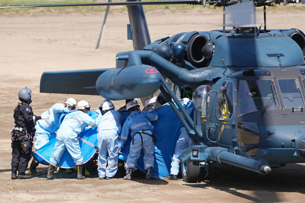 24日、自衛隊ヘリから救助された人を搬送する救急隊員ら（Ｃ）共同通信社
