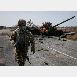 破壊したロシア軍の戦車の前を歩くウクライナ軍兵士（Ｃ）ロイター