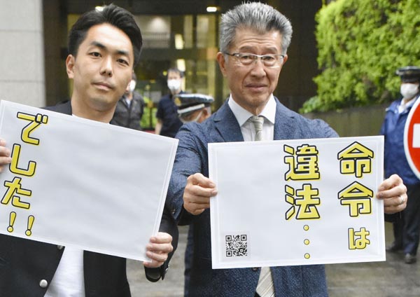 東京地裁前でボードを掲げるグローバルダイニングの長谷川耕造社長（右）ら（Ｃ）共同通信社