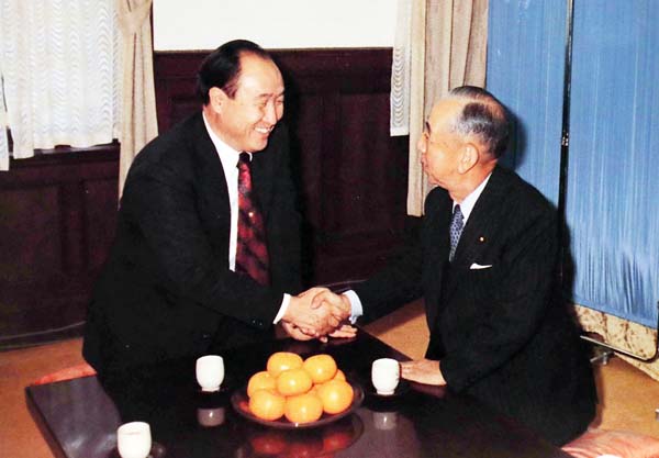 握手を交わす岸信介元首相（右）と文鮮明・旧統一教会創立者（「統一教会四十年史」より複写）
