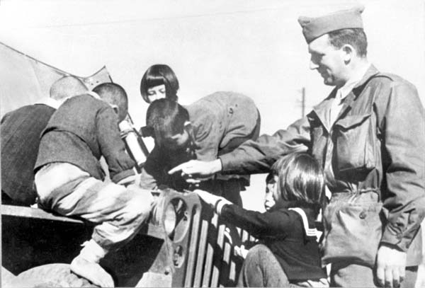 終戦後、子供たちは無心に兵士に群がり、チョコレートやチューインガムをもらった＝1945年（Ｃ）共同通信社