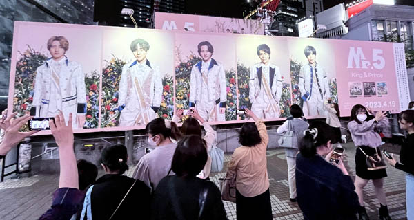 King＆Princeのラストアルバムリリース広告の前で写真を撮るファン（Ｃ）日刊ゲンダイ