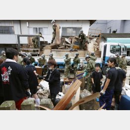 熊本県人吉市の市街地で、泥にまみれた家財道具などを撤去する地域住民のボランティアと自衛隊員（2020年7月）／（Ｃ）共同通信社