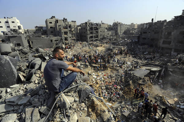 1日、パレスチナ自治区ガザ北部のジャバリヤ難民キャンプで、イスラエル軍の空爆を受けてがれきとなった場所に座る男性（Ｃ）AP＝共同