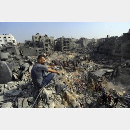 1日、パレスチナ自治区ガザ北部のジャバリヤ難民キャンプで、イスラエル軍の空爆を受けてがれきとなった場所に座る男性（Ｃ）AP＝共同