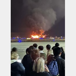 羽田空港の滑走路で炎上する日航機から離れ、待機する516便の乗客たち（Ｃ）日刊ゲンダイ／中西直樹