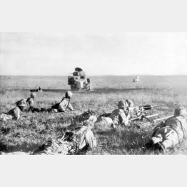 満州国とモンゴル人民共和国（外蒙古）の国境係争地であるノモンハンでの戦闘で、ソ連軍が遺棄した戦車の側を匍匐前進する日本軍兵士（1939＝昭和14＝年7月）／（Ｃ）共同通信社