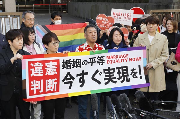 3月14日、同性婚を巡る東京第２次訴訟の判決後、東京地裁前でメッセージを掲げ取材に応じる原告ら（Ｃ）共同通信社