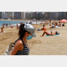 スペイン・グランカナリア島のビーチでマスクをつけ歩く女性（Ｃ）ロイター