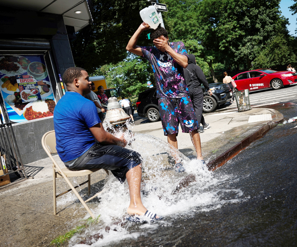 ニューヨーク市マンハッタンのワシントンハイツ地区で、消火栓の水で涼む若者たち（Ｃ）ロイター