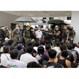 ミャンマー東部の詐欺拠点で大勢の外国人が解放された(=手前。奥は少数民族勢力「国境警備隊(BGF)」の幹部ら)/(BGF関係者提供、共同)