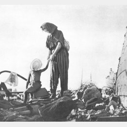 戦災のがれきの上に立つ母子 大分の空襲(1945=昭和20=年ごろ、大分県) (C)大分合同新聞社/共同通信イメージズ