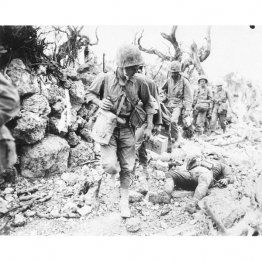 日本兵の遺体を横目に前線に進軍する米兵（Ｃ）共同通信社